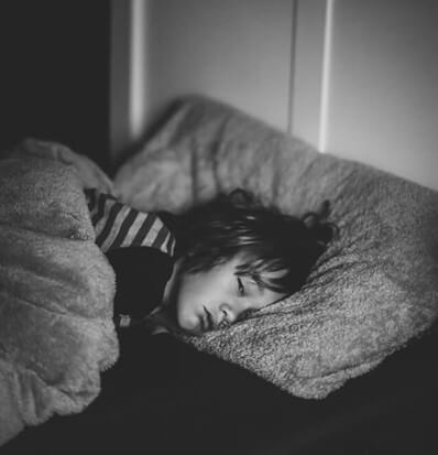 ילד שוכב עצוב במיטה